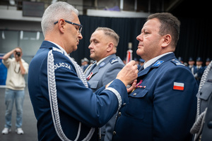 Komendant Wojewódzki Policji w Katowicach przypina medal do munduru nagrodzonemu policjantowi