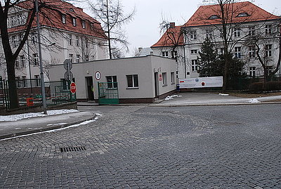 Zdjęcie kolorowe. Budynek parterowy usytuowany przy wjeździe do Oddziału Prewencji Policji w Katowicach.