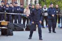 Policjant gotowy do startu do biegu. W tle stoją policjanci.