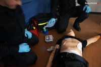 Dwóch policjantów klęczy nad fantomem.