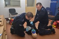 Dwóch policjantów klęczy nad fantomem