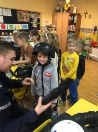 Policjant prezentuje dzieciom sprzęt policyjny.