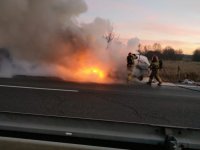 Strażacy gaszący palący się samochód.