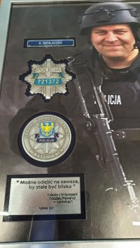 Zdjęcie kolorowe. Tablica pamiątkowa z wizerunkiem policjanta.