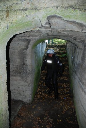 Policjant w pełnym sprzęcie PZ zbiega do bunkra.