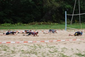 w policjantów czołga się po boisku do siatkówki plażowej.