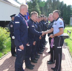 Mężczyzna w mundurze Policji Czeskiej składa gratulacje osobie w mundurze polskiego policjanta. W ręku trzyma medal na wstążce.