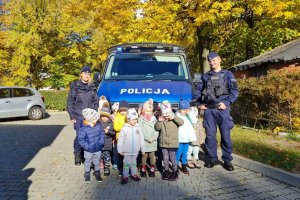 Zdjęcie grupowe dzieci z policjantami na tle radiowozu.