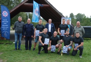 Zdjęcie pamiątkowe drużyny, która zajęła drugie miejsce z dowódcą Oddziału Prewencji Policji w Katowicach inspektorem Rafałem Stankiem, jego zastępcą młodszym inspektorem Arturem Maliszewskim i Burmistrzem miasta Łazy Maciejem Kaczyńskim. W rękach zawodników puchar i dyplomy.