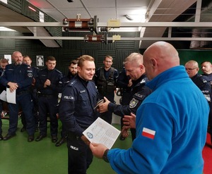 Zastępca Dowódcy Oddziału Prewencji Policji w Katowicach młodszy inspektor Artur Maliszewski wraz z Przewodniczącym Zarządu Terenowego Niezależnego Samorządnego Związku Zawodowego Policjantów Oddziału Prewencji Policji w Katowicach aspirantem sztabowym Dariuszem Tabasem wręczają pamiątkową statuetkę i dyplom najlepszemu strzelcowi wśród instruktorów młodszemu aspirantowi Krystianowi Kotowiczowi.