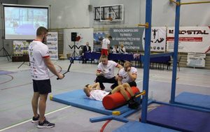 Aspirant Adam Biedziak w trakcie wykonywania brzuszków. Obok sędziowie mierzący czas i starszy sierżant Wojciech Obtułowicz nagrywający konkurencję.