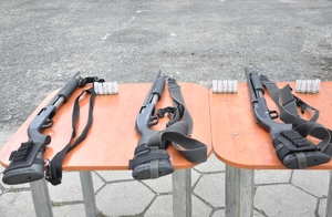 3 sztuki broni gładkolufowej Mossberg i 15 sztuk amunicji niepenetracyjnej leżą na stoliku.