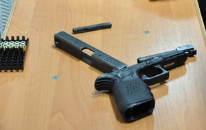 Pistolet Glock rozłożony na stoliku. Obok amunicja w koszyczku.