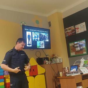 Policjant przy pomocy prezentacji multimedialnej omawia elementy umundurowania.