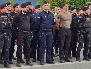 Grupa osób w mundurach stoi w szyku. Widok z przodu. Widocznych jest trzech policjantów w polskich mundurach.