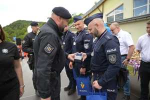Na zdjęciu trzech policjantów w polskich mundurach. Mają na szyi medale. Osoba w mundurze wręcza statuetkę jednemu z policjantów.