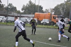 Zawodnicy Kompanii Prewencji II i Kompanii Prewencji IV na boisku podczas gry. W tle sędzia.