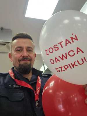 Podkom. Mateusz Derela z balonem z napisem "zostań dawcą szpiku".