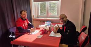 Policjant w koszulce DKMS informuje potencjalnego dawcę o warunkach pobrania wymazu.