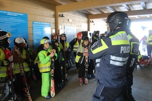 Policjanci omawiają z dziećmi zasady bezpieczeństwa na stoku.