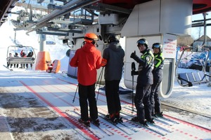 Policjanci wraz z 2 uczestnikami obozu czekają na krzesełko w dolnej stacji wyciągu.