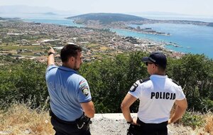 Dwóch policjantów z Polski i Chorwacji na wzgórzu. Funkcjonariusz chorwacki gestem ręki wskazuje polskiemu policjantowi podległy rejon patrolowania.