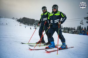 Dwóch policjantów na nartach podczas patrolu narciarskiego.