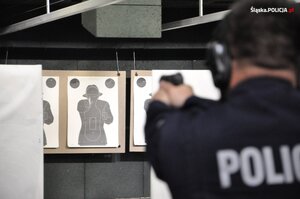 Funkcjonariusz podczas szkolenia na strzelnicy oddaje strzał. W tle tarcza.