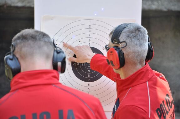 Dwóch sędziów przy tarczy zlicza punkty na podstawie przestrzelin.