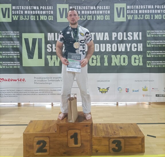 Sierżant. Maciej Tworzydło ze złotym medalem i dyplomem na najwyższym stopniu podium.